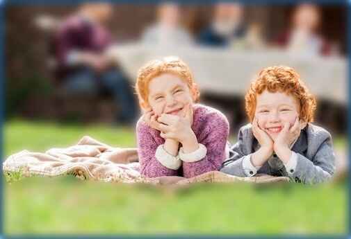 Children sitting on blanket outside listening to storytelling.