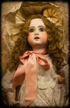 Antique baby doll with long brown wavy hair.