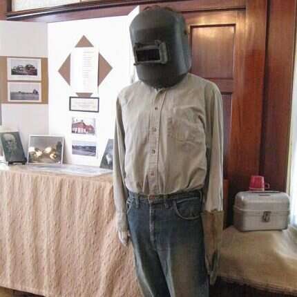 Photo of forge worker wearing industrial clothing and a welding hood.