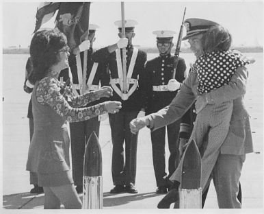 Robert Harper Shumaker returning home holding child in his arms and being greeted by his wife with military guard standing in background.