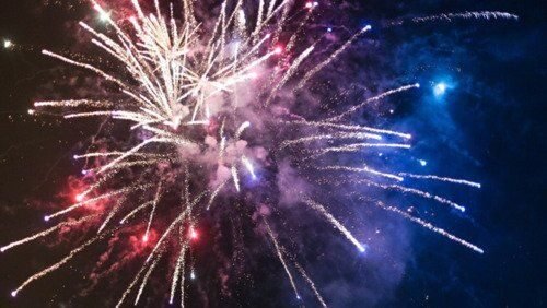 Bright exploding fireworks in the dark night sky.