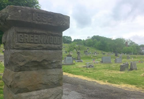 greenwood cemetery entrance pillar with cemetery hillside in background